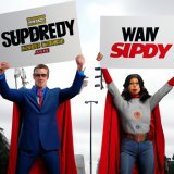 Sabitzer and Jihyo, dressed as Superman and James Gunn, are standing before The Authority, wielding #DCStudios signs. "NETFLIX, reverse your decision!" Sabitzer and Jihyo chant in unison, a plea for Wayne to get his rightful spot in the company. Supe