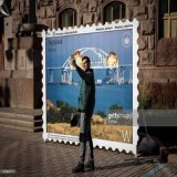 People near the #Kyiv City Hall are photographed against the background of a large postage stamp depicting the explosion of the Crimean Bridge.