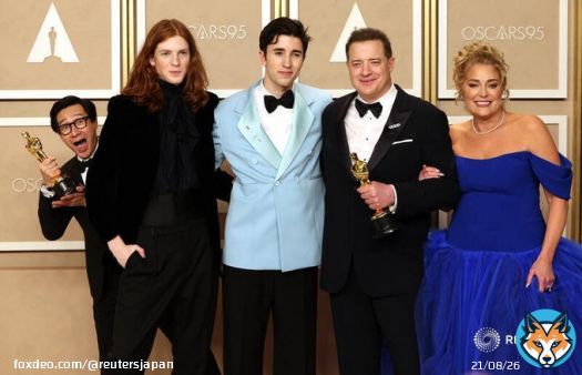 第95回米アカデミー賞授賞式で、ブレンダン・フレイザー（主演男優賞）が息子、パートナーと写真を撮影する中、後ろから姿を見せるキー・ホイ・クァン（助演男優賞）。ハリウッドで12日撮影。REUTERS/Mike Blake