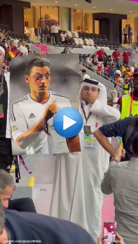 A fan goes around the Germany fans holding up a poster of Mesut Ozil and covering his mouth.