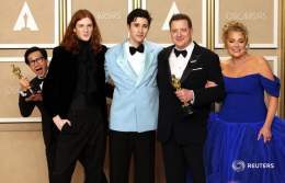 第95回米アカデミー賞授賞式で、ブレンダン・フレイザー（主演男優賞）が息子、パートナーと写真を撮影する中、後ろから姿を見せるキー・ホイ・クァン（助演男優賞）。ハリウッドで12日撮影。REUTERS/Mike Blake